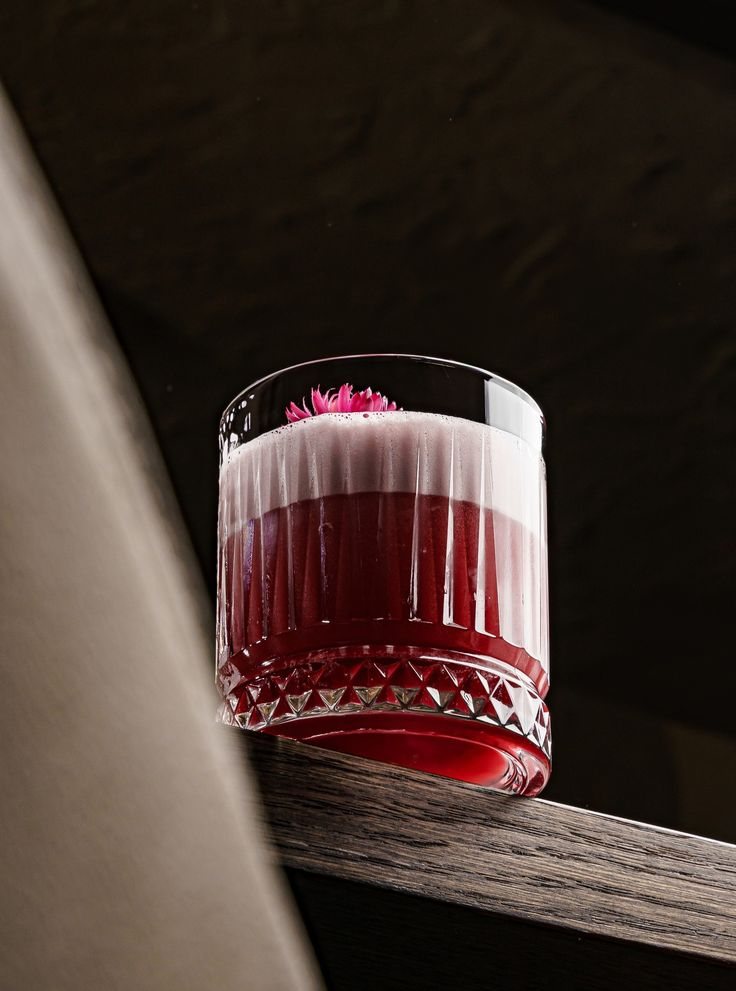 Un cocktail rosso servito in un bicchiere cesellato